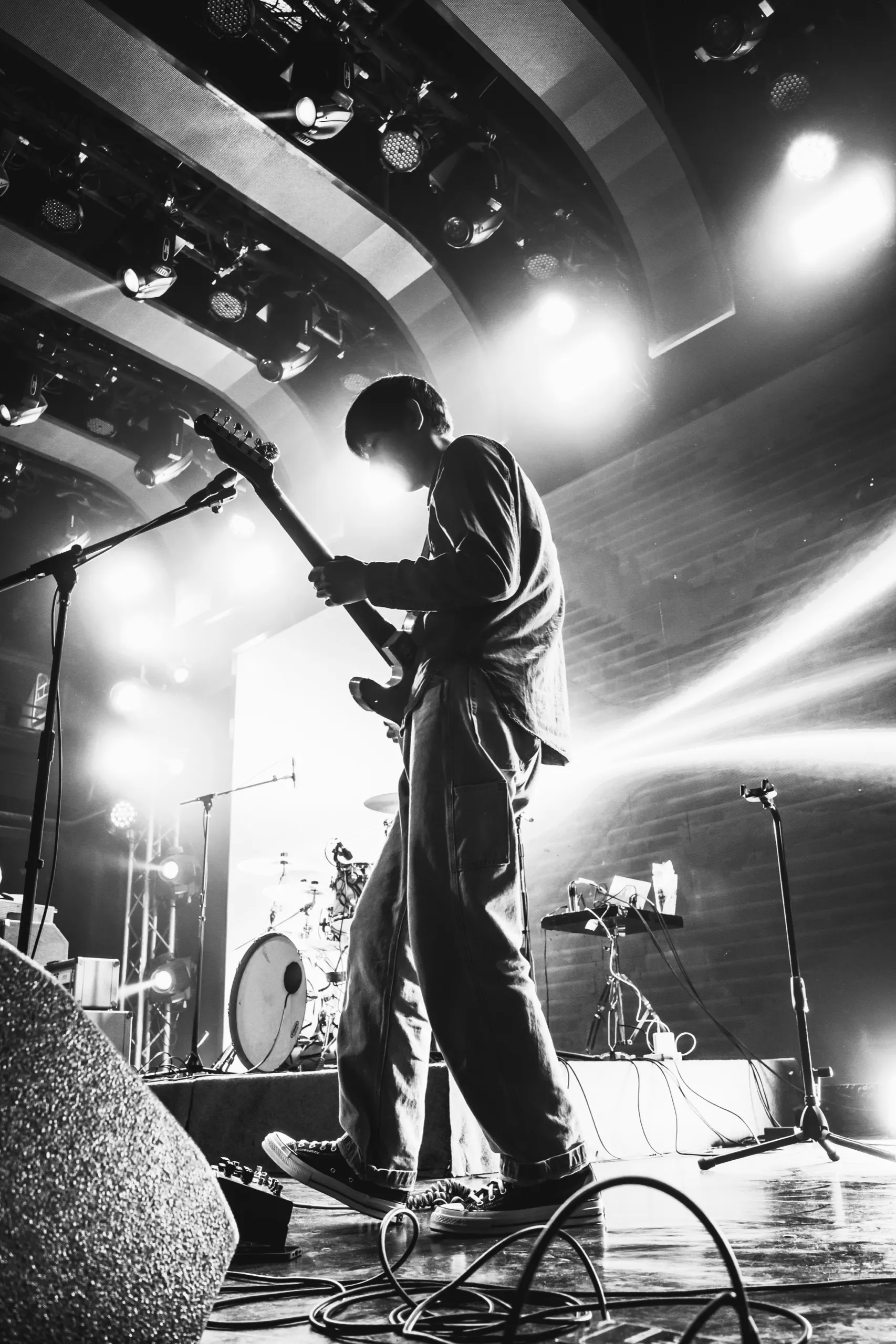 Black-and-white low-angle shot of a guitarist playing into the stage lights
